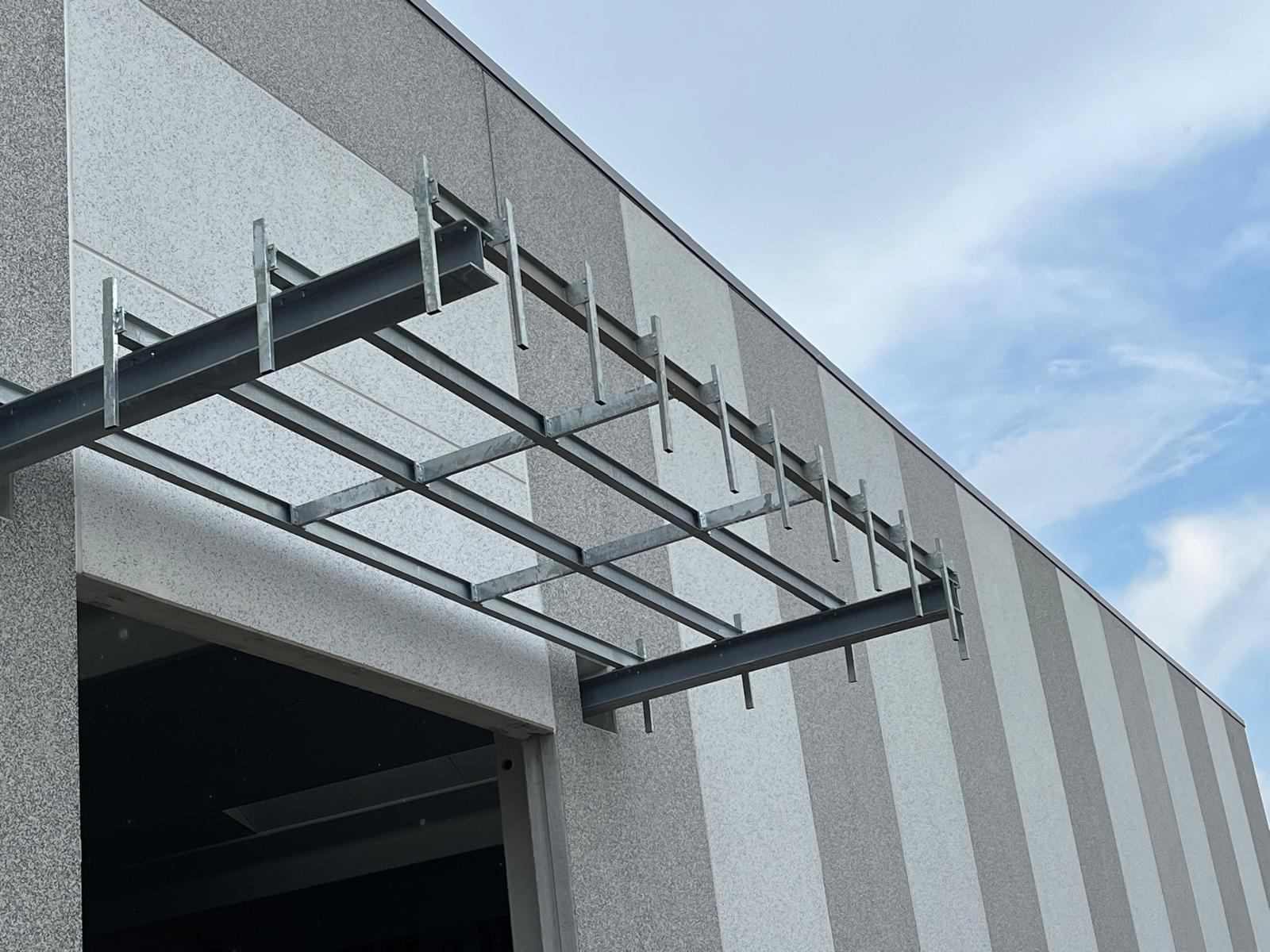 Struttura in acciaio per magazzino in fase di montaggio con gru e squadra operativa